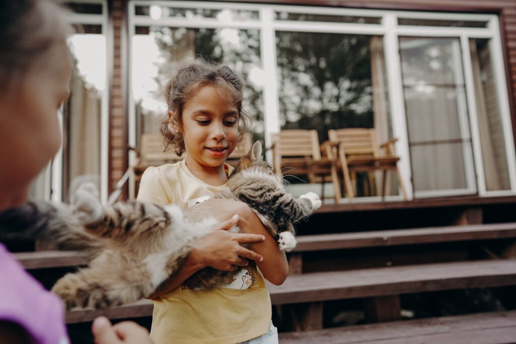 Portrait of a child with a kitten in his arms outdoors. Children and pets